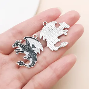 Detailed close-up showing front and back of gothic dragon charms on a palm