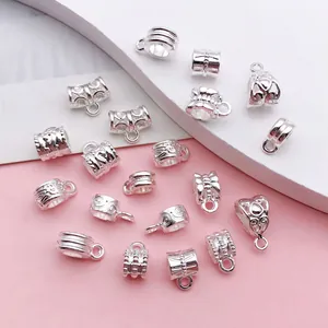 Close-up of vintage silver alloy charm bails featuring various engraved patterns for DIY