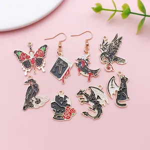 Detailed view of Gothic black enamel charms featuring dragons, crows, and cats in gold finish