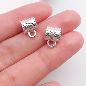 Close-up view of two silver-colored retro bail beads showing detailed embossed patterns.