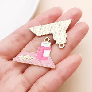 Close-up of pink and gold enamel medicine bottle charms for jewelry making