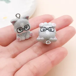 Close-up detail of two cute gray cartoon cat resin charms with glasses for DIY crafts.