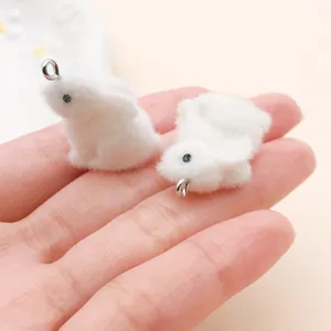 Gros plan de mini breloques lapin en peluche blanche pour bijoux DIY sur une paume