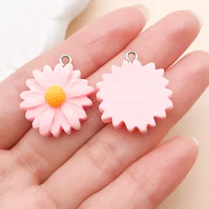 Gedetailleerd zicht op roze madeliefjes harsbedeltjes met voor- en achterkant voor DIY.