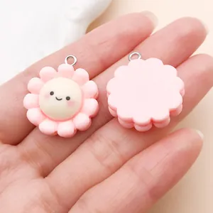 Twee leuke roze bloem bedeltjes van hars met smileys voor het maken van DIY sieraden.