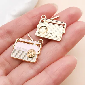 Vue détaillée de breloques radio rétro en émail rose et doré pour bijoux DIY.