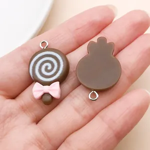Close-up detail view of cute chocolate resin lollipop charms with pink bow for DIY jewelry