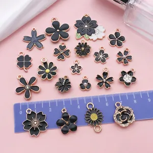 Detail view of black enamel flower charms featuring daisy and cherry blossom for DIY jewelry
