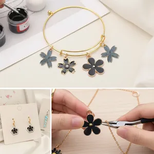 Detailed macro view of black enamel flower charms being assembled into DIY jewelry