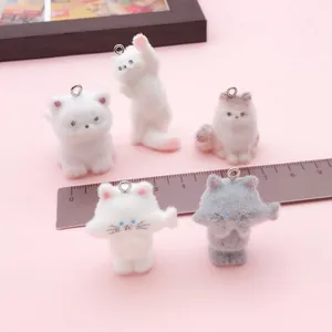 Vista detallada de mini dijes de gatos con regla para referencia de escala y textura.