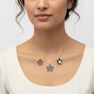 Close-up of an elegant gold necklace with three colorful enamel flower pendants on model