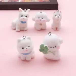 Detalle de cinco dijes de perro blanco flocado, incluyendo un Westie y un Bichon Frise.