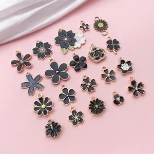 Close-up of black enamel flower pendants including cherry blossoms and daisies