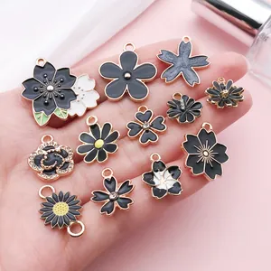 Detailed view of black enamel flower charms including sakura and daisy for DIY jewelry