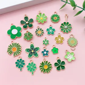 Gros plan sur des breloques en émail vert fleurs et trèfles pour la création de bijoux.