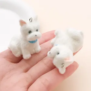 Primer plano de dos pequeños dijes de perro Westie flocados blancos para manualidades