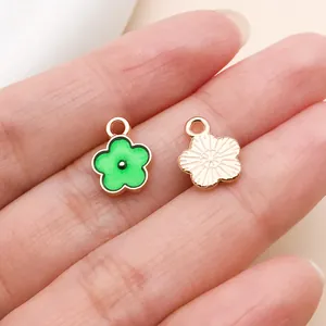 Détail de petits pendentifs fleurs en émail vert pour la création de bijoux et boucles.