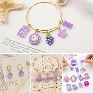 Dettaglio di vari ciondoli in resina viola con orsi e fiori per gioielli fai-da-te.