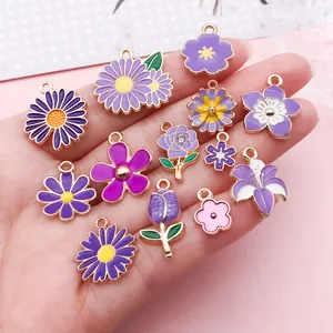 Collection de breloques florales violettes pour bijoux DIY montrée sur une main.