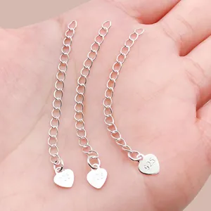 Macro-opname van drie zilveren verlengkettingen met hartlabel voor doe-het-zelf sieraden.