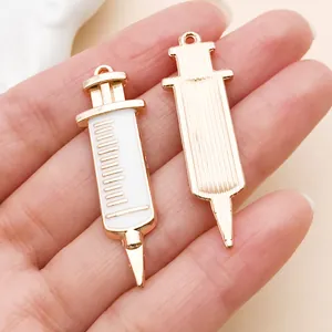 Detailansicht von Emaille-Spritzenanhängern für medizinischen DIY-Schmuck in Goldweiß.