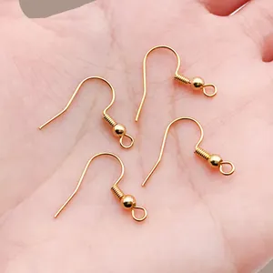 Detailed macro shot of four 18k gold-plated copper fish hook earring findings on a hand