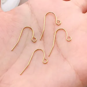 Close-up view of four 18k gold-plated copper French earring hooks held in a palm