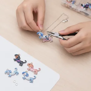 Hands using pliers to attach a dachshund dog pendant to a silver chain for DIY jewelry.