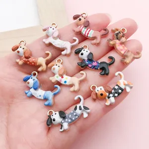 Hand mit bunten Cartoon-Dackel-Welpen-Anhängern für die eigene DIY-Schmuckherstellung.