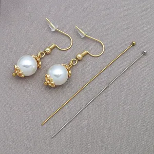 Close-up detail of stainless steel gold ball head pins and white pearl drop earrings
