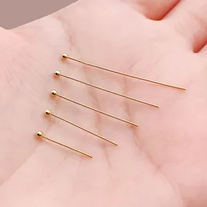 Primer plano de cinco alfileres con cabeza de bola bañados en oro de 18 quilates.