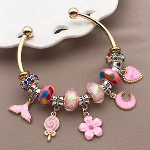 Detalle de cerca de una pulsera de dijes dorada con colgantes de flores rosas