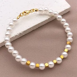 Detailansicht eines weißen Perlenarmbands mit goldenen quadratischen Edelstahlabstandhaltern