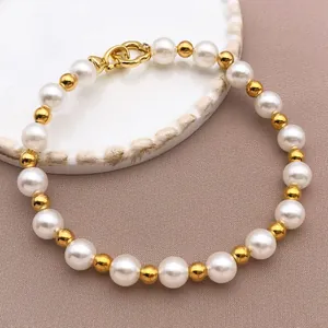 Nahaufnahme eines eleganten Armbands mit weißen Perlen und goldenen Perlen-Details