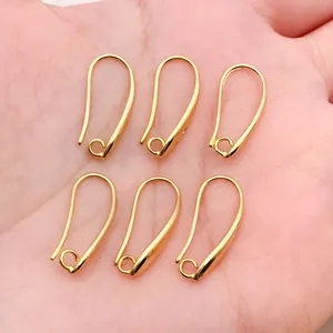 Macro detail of six 18k gold plated copper earring hooks held in an open palm.