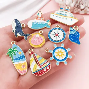 Vista detallada de dijes náuticos de esmalte con ballena, velero y tabla de surf DIY