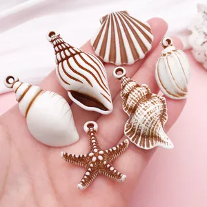 Primer plano de varios colgantes de acrílico con forma de concha y estrella de mar.