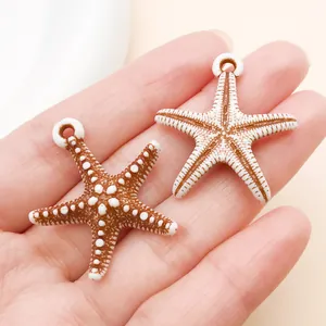 Primer plano de dos colgantes de estrella de mar de acrílico en marrón y blanco para joyería DIY
