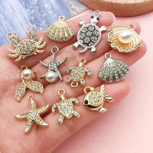 Detailed macro view of assorted ocean-themed charms with sparkling rhinestones held in a hand