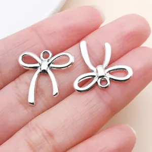 Detalle de dos colgantes de lazo plateados de estilo vintage para joyería y proyectos DIY.
