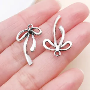 Primer plano de dijes de lazo de plata antigua para accesorios de joyería DIY.