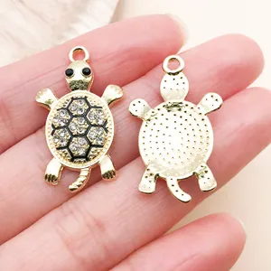 Detailed close-up showing front and back of gold turtle charms with rhinestones for DIY jewelry