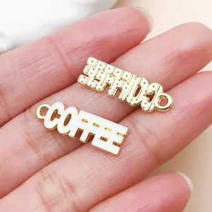 Close-up of white enamel and gold-toned coffee letter charms for DIY jewelry