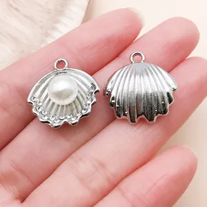 Macro view of a silver-toned shell pendant featuring a white pearl and clear rhinestones.