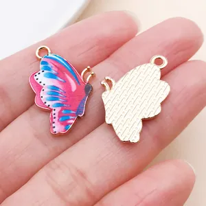 Primo piano di ciondoli a farfalla rosa e blu che mostrano fronte e retro inciso.
