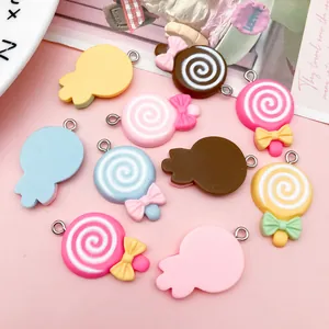 Close-up view of assorted colorful resin lollipop charms with bows and metal hanging loops