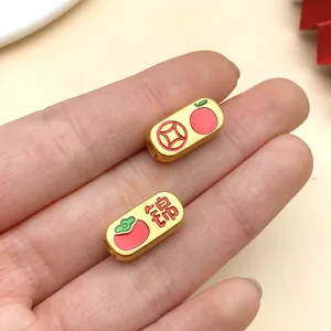 Nahaufnahme chinesischer goldener Rechteckperlen mit emaillierten Obst- und Münzsymbolen