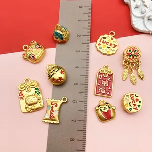 Close-up of gold-plated lucky cat charms with ruler showing size and colorful enamel detail
