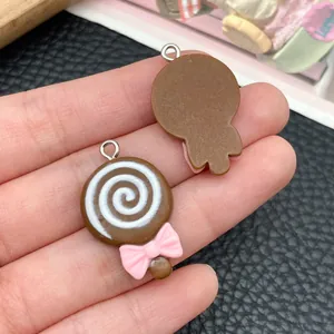 Detail view showing front and back of brown lollipop resin charms with pink bows.