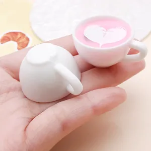 Detailed macro shot of miniature resin coffee cup charm with pink heart latte art